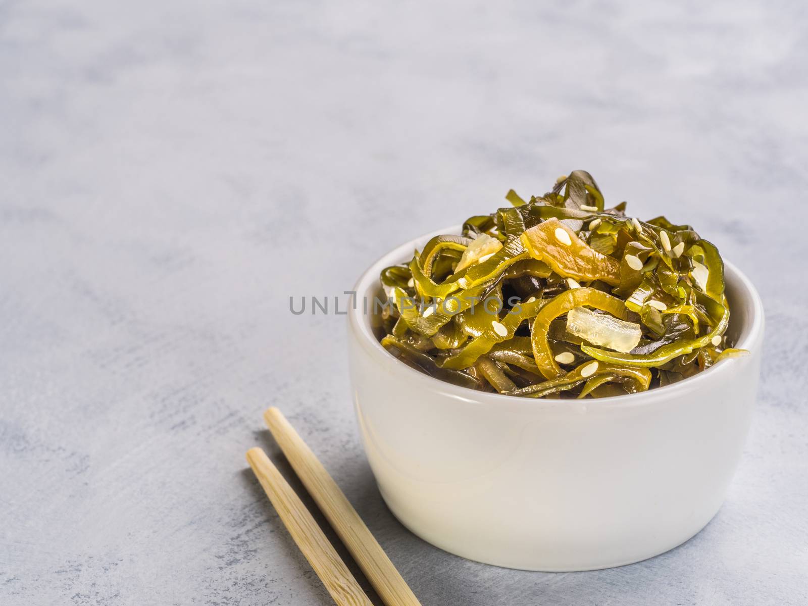 Close up view of kelp seaweed salad with sesame seeds on gray concrete background. Copy space.