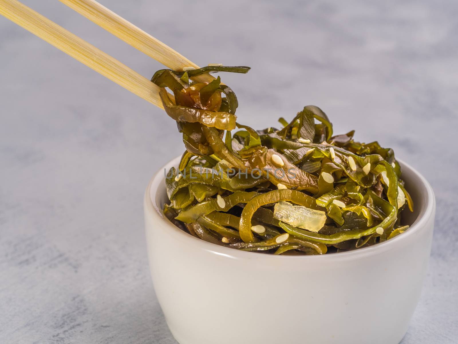 Close up view of kelp seaweed salad with sesame seeds on gray concrete background. Copy space.