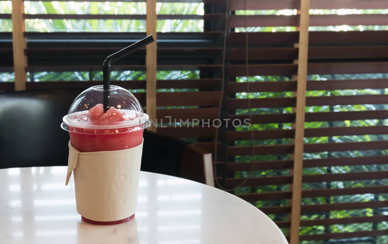 Closeup of watermelon smoothie in plastic glass on table, selective focus