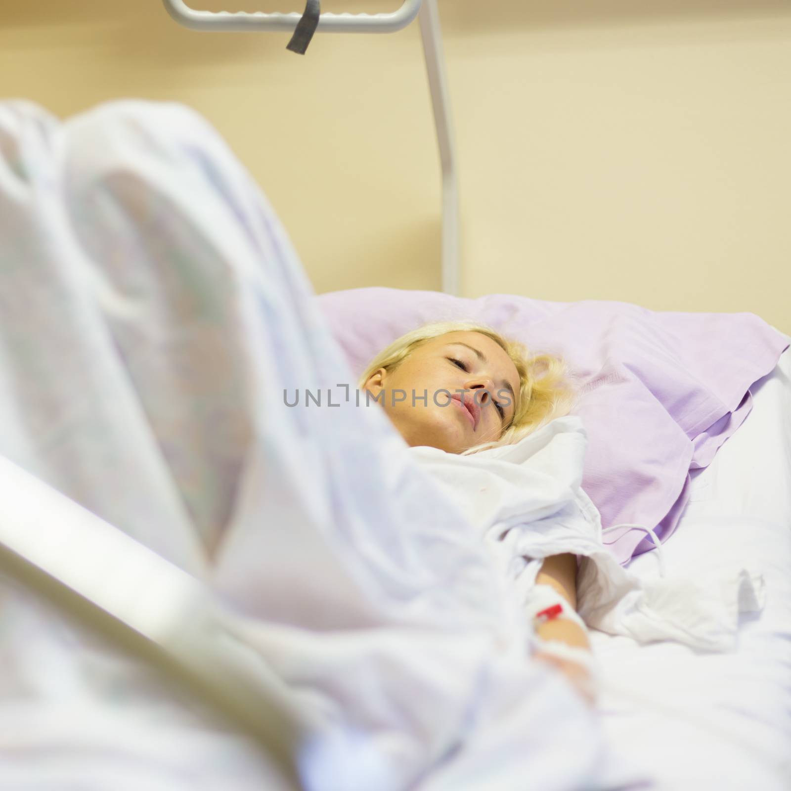 Bedridden female patient recovering after surgery in hospital care. by kasto