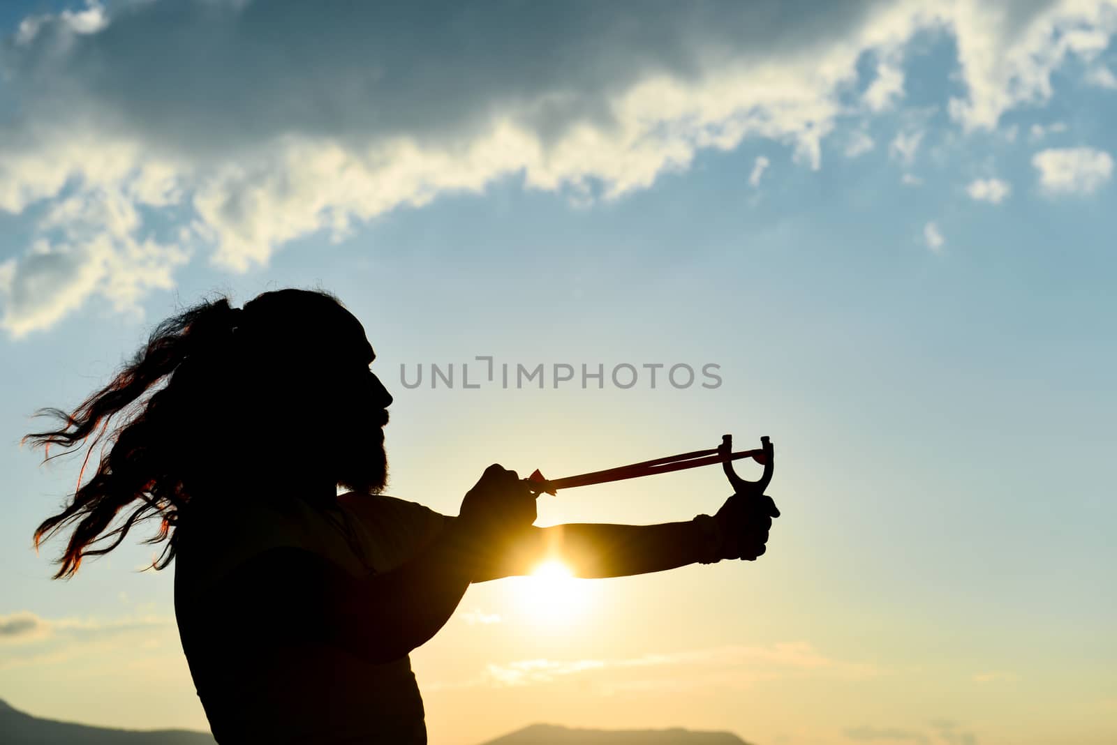 silhouette of the man who throws slingshot by crazymedia007