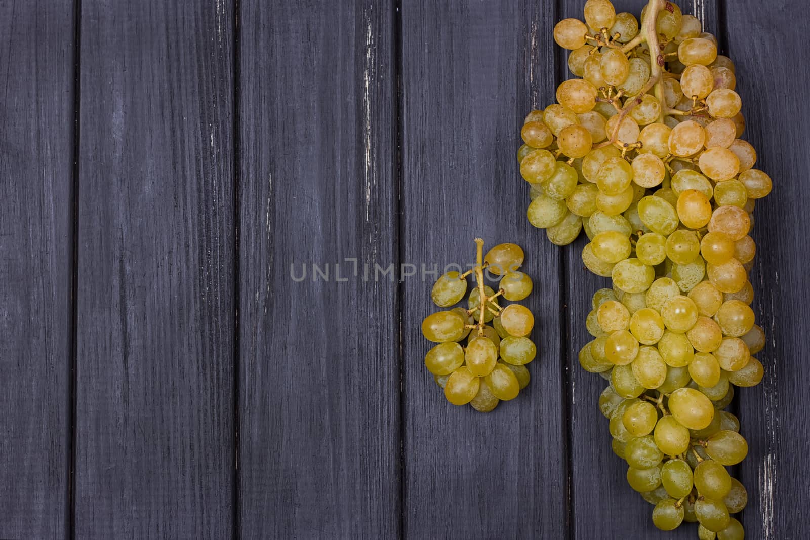 bunch of white grapes on a black wooden background. Rustic style. Place for text. copy-space