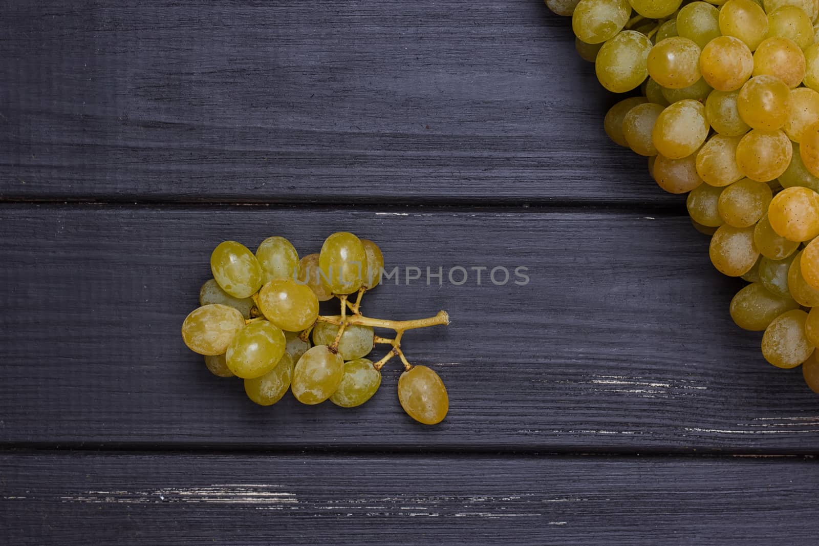 bunch of white grapes on a black wooden background by victosha