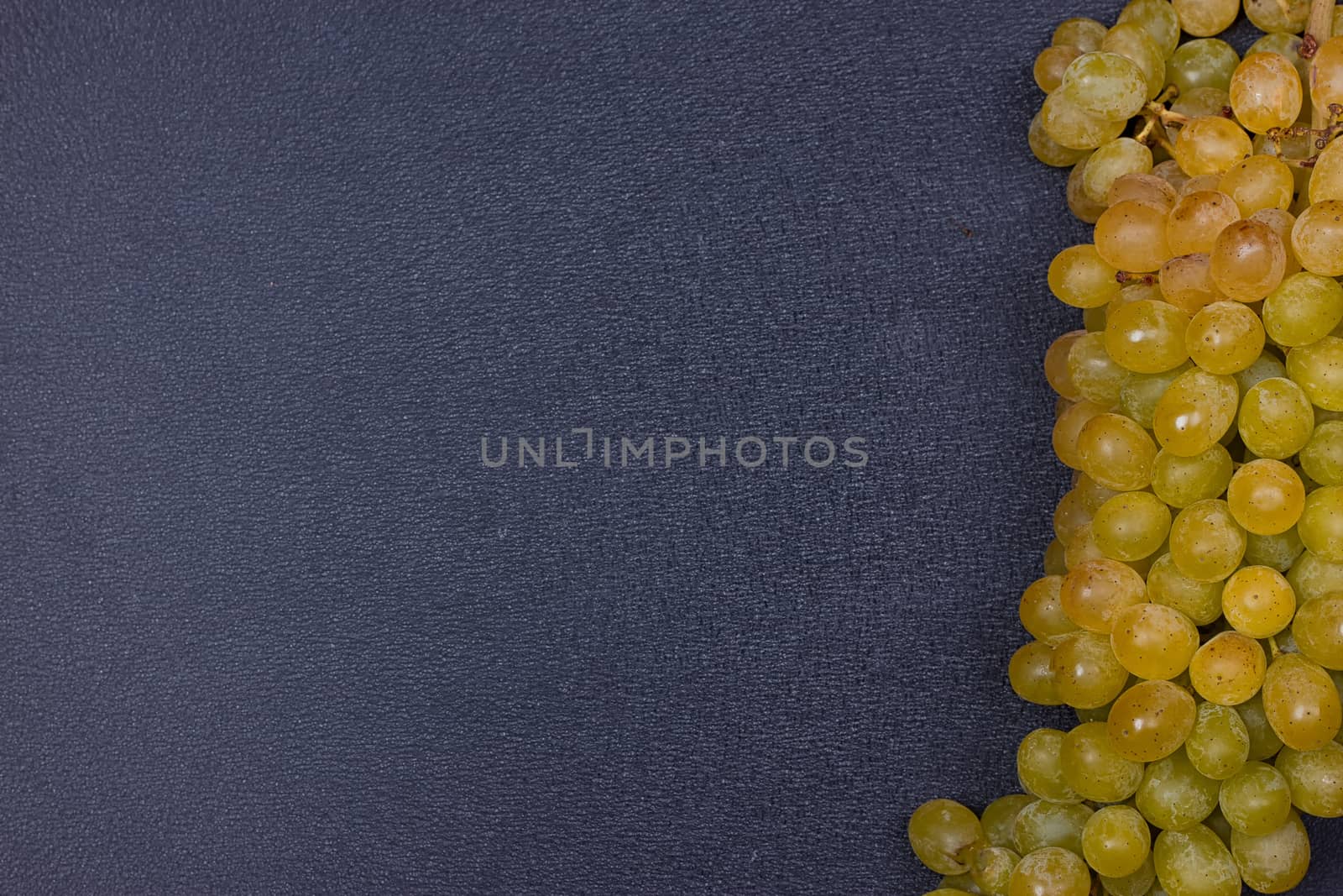 Large grapes cluster amber color on black background. copy-space