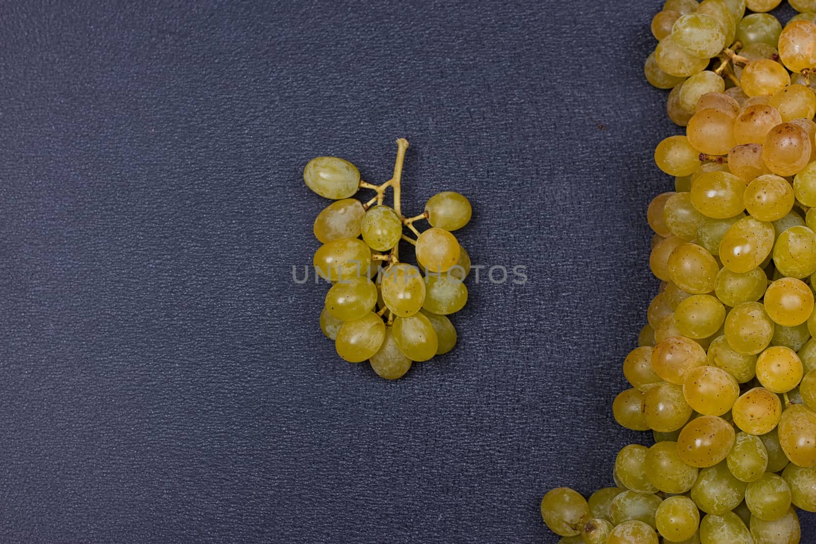 Large grapes cluster amber color on black background. copy-space