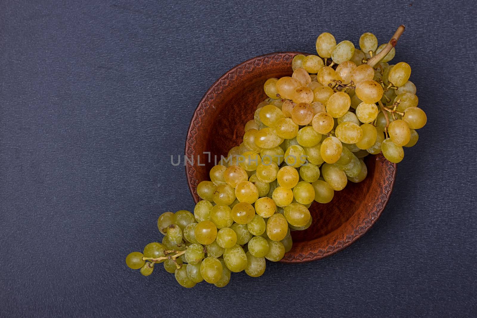 Bowl with a bunch of white grapes on black table. copy-space