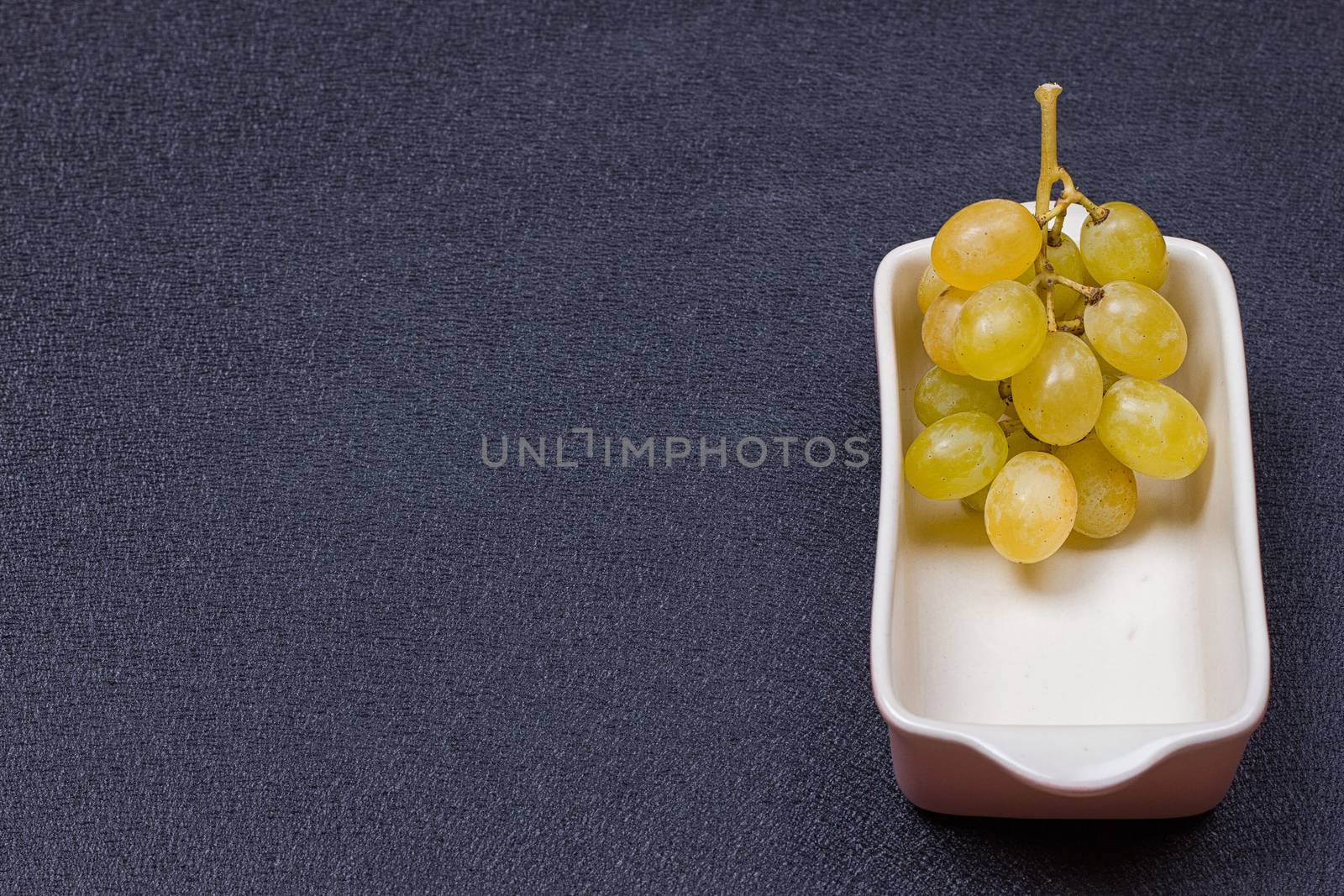 White grapes in a bowl on a black background.copy-space