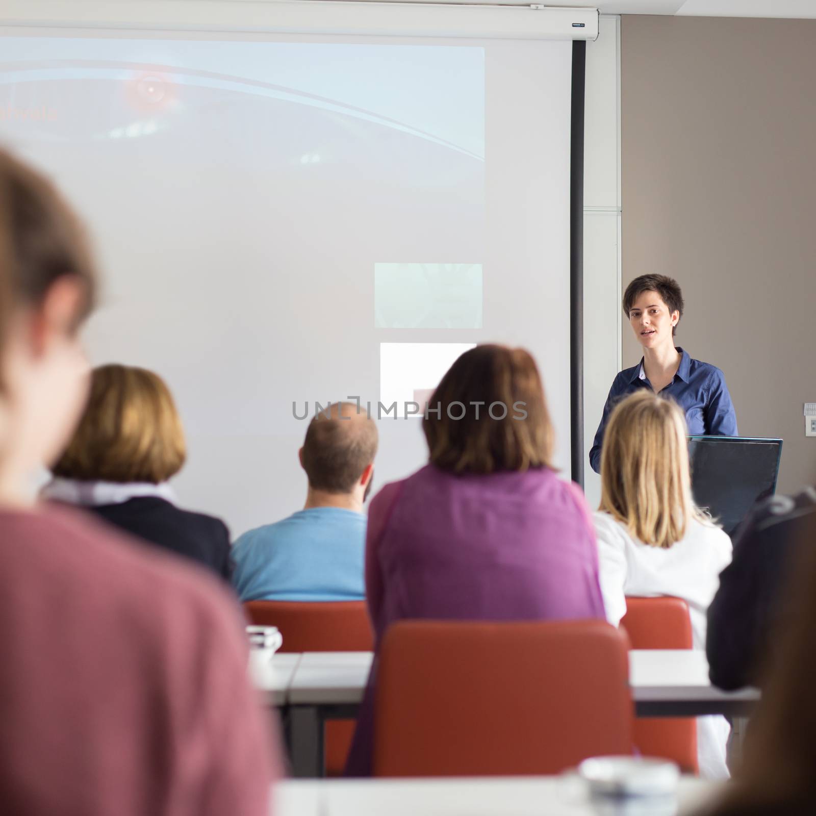 Woman giving presentation in lecture hall at university. by kasto