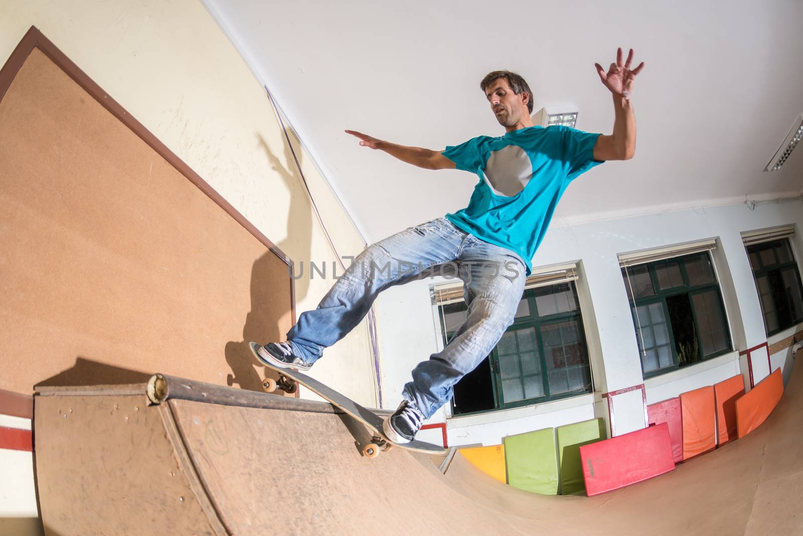 Skateboarder performing a trick on mini ramp at indoor skate park.