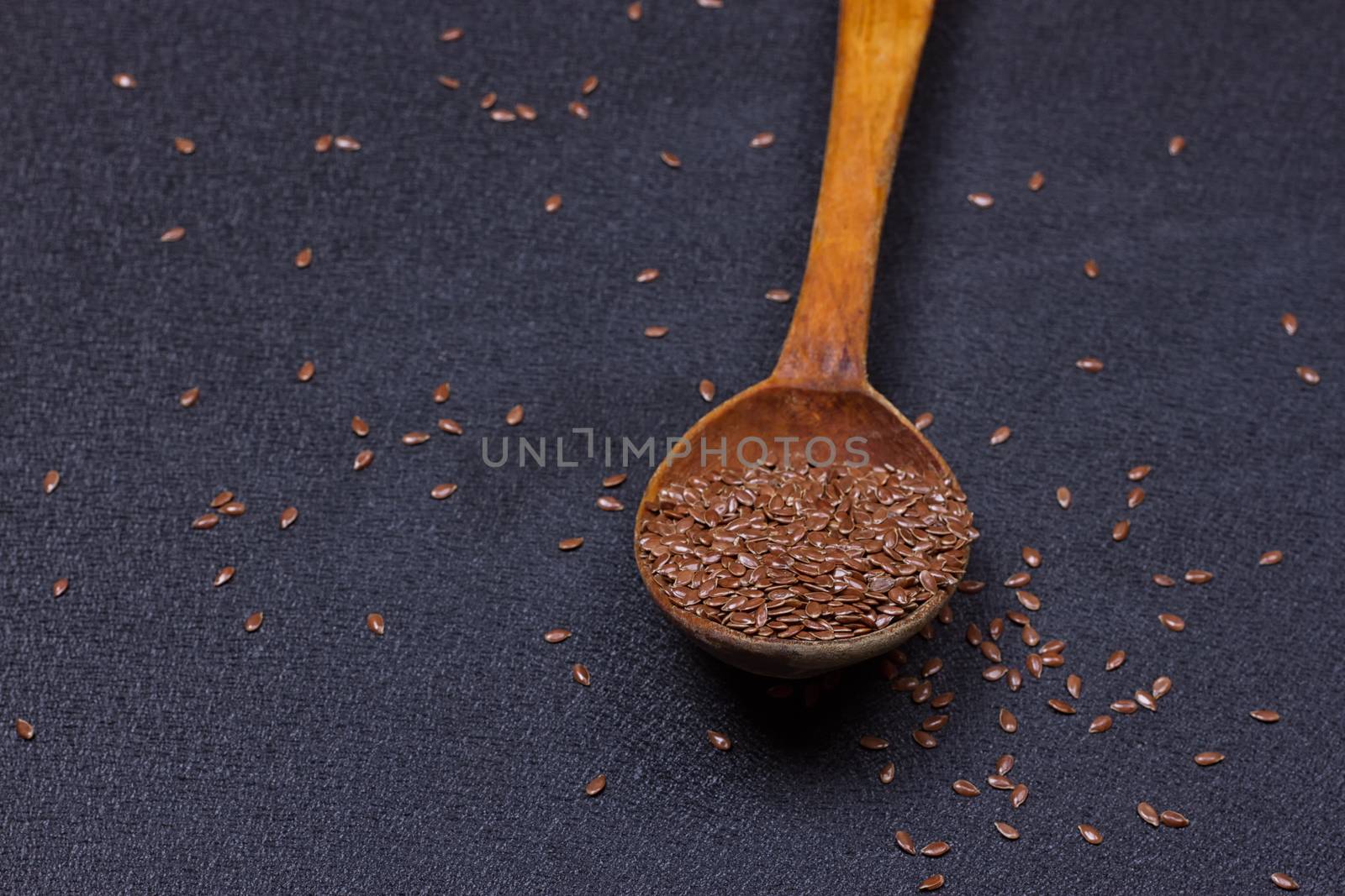 wooden spoon with flax seed placed on a black table