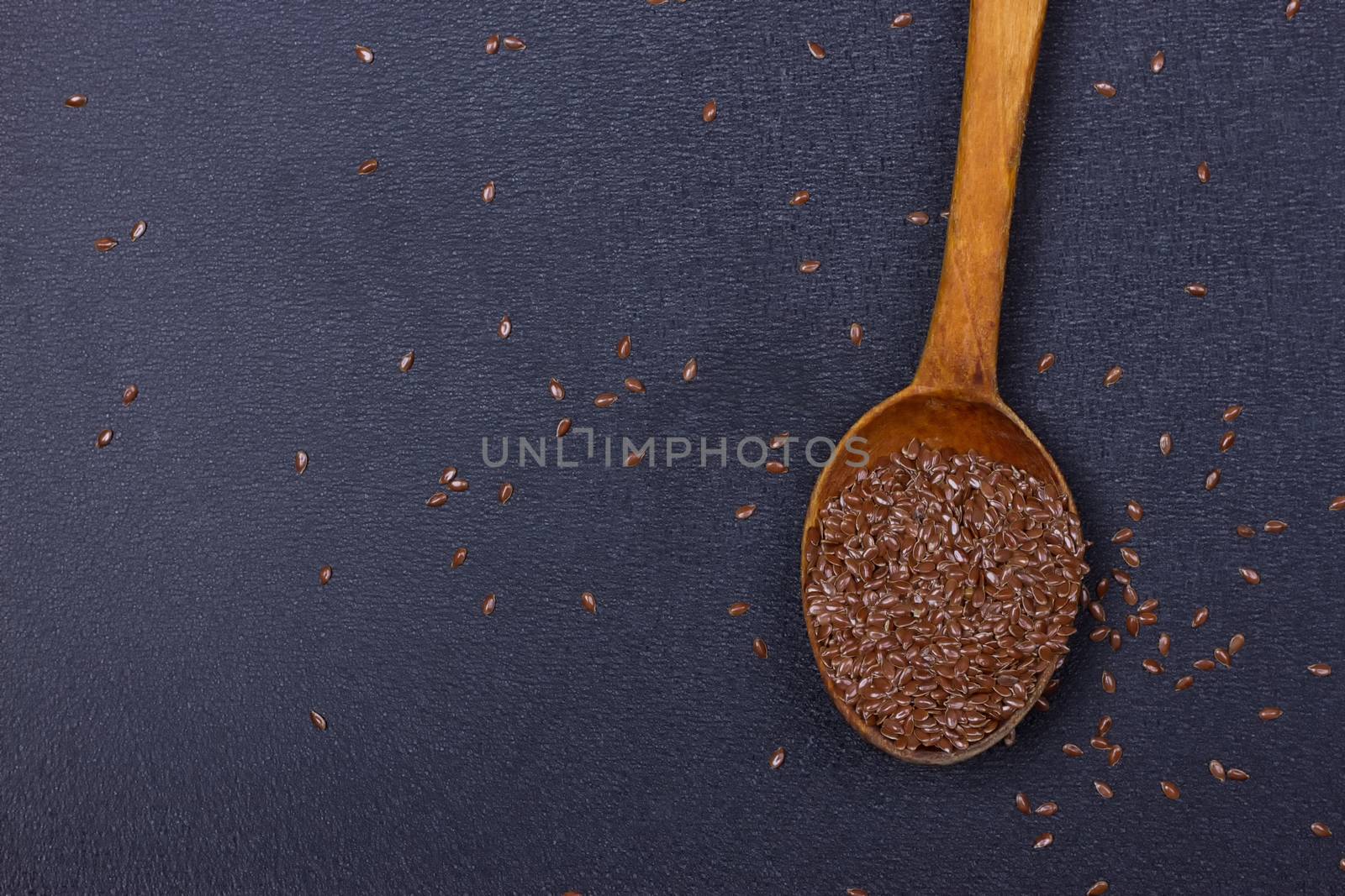 wooden spoon with flax seed placed on a black table