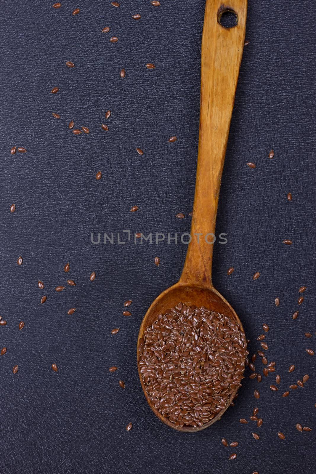 wooden spoon with flax seed placed on a black table