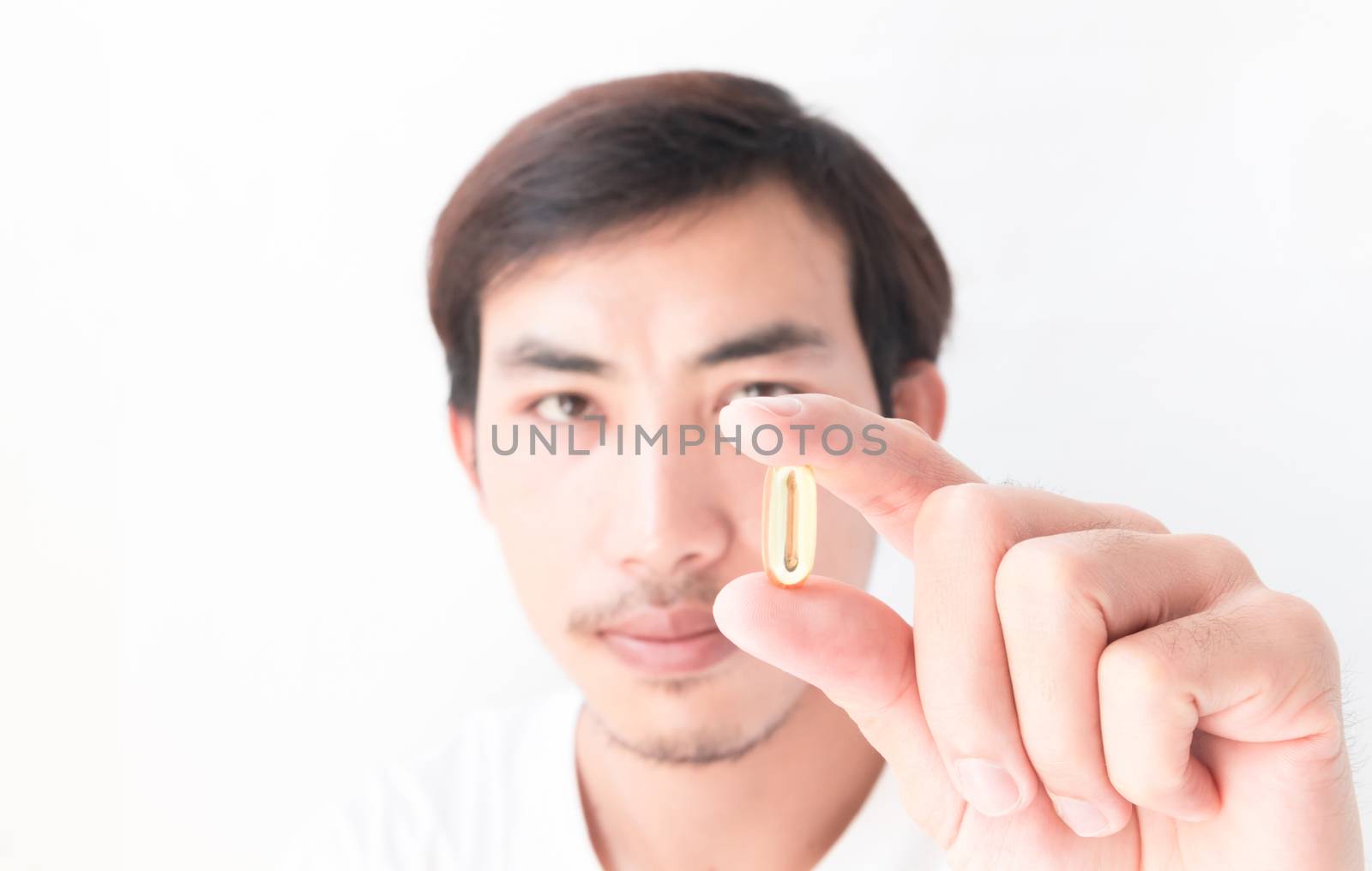 Closeup man hand holding fish oil medicine with white background by pt.pongsak@gmail.com