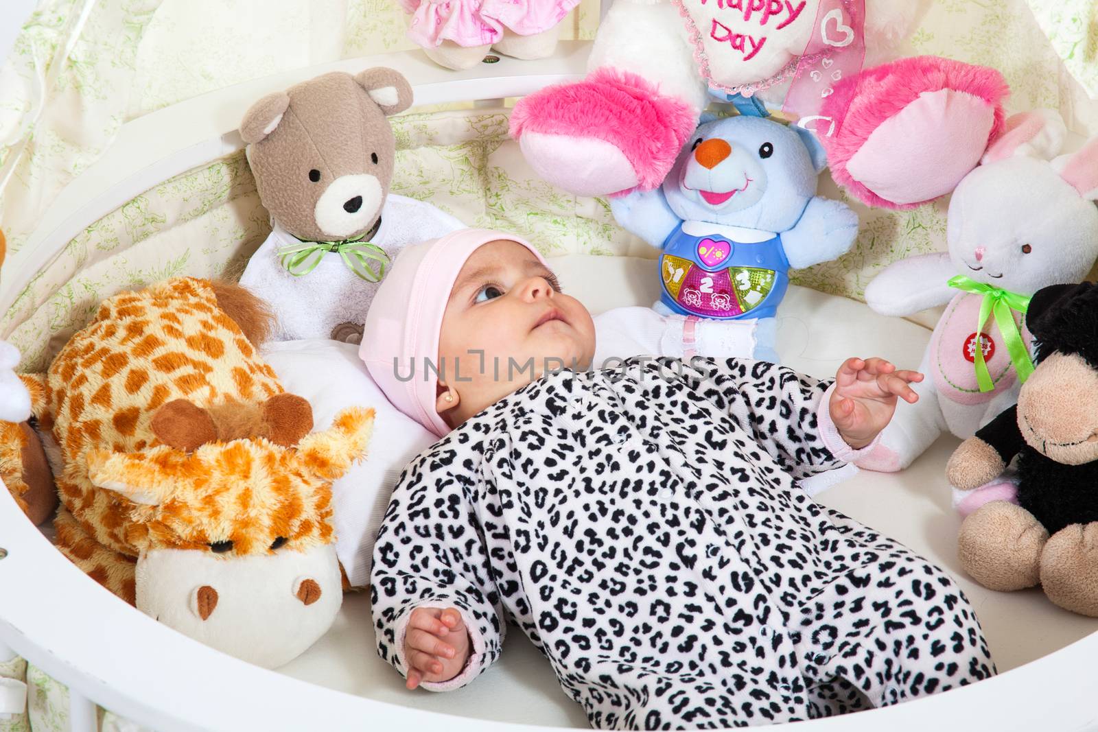 A baby girl dressed in animal print surrounded by stuffed animals