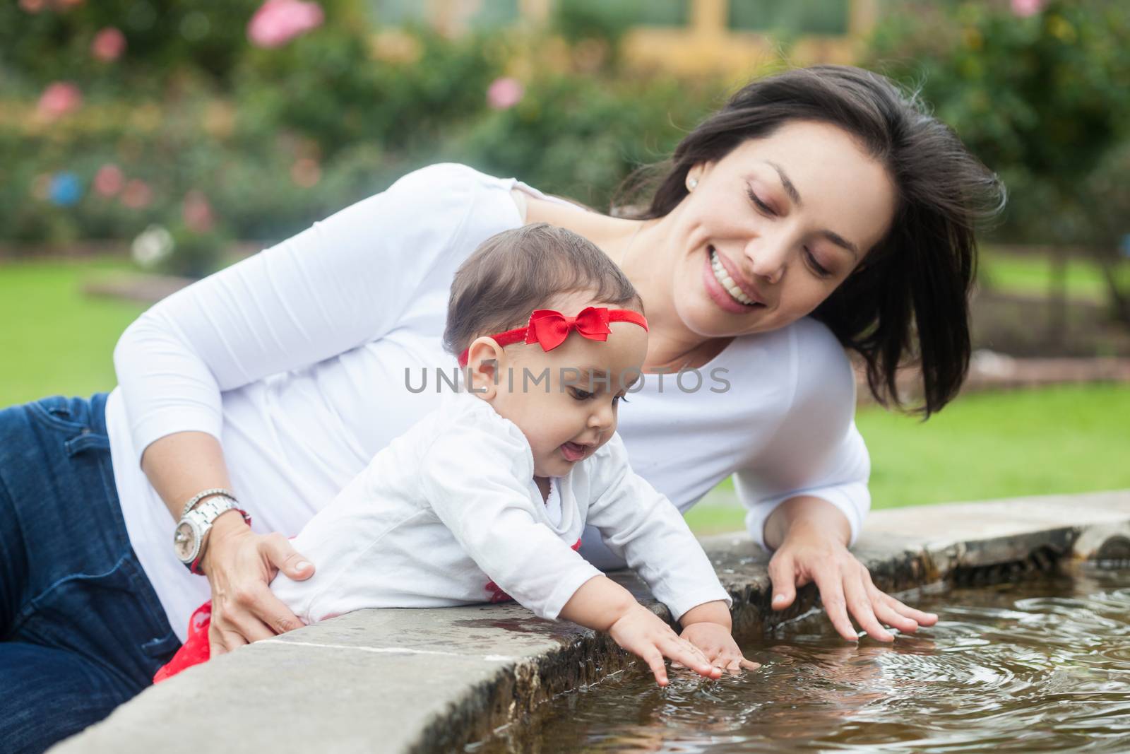 Baby girl and her mom playing with water