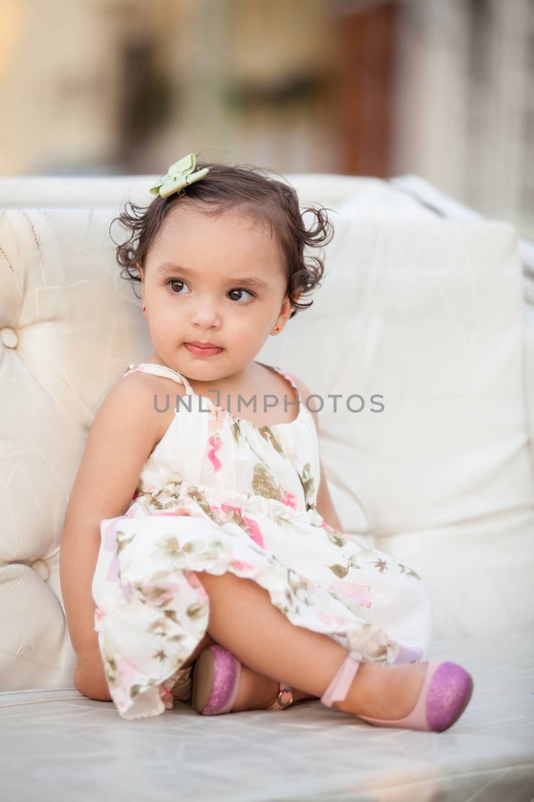 Baby girl wearing a floral dress sitting on a horse carriage