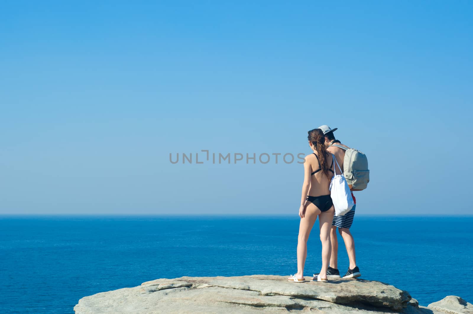 Hikers with backpacks enjoying the view of ocean. Traveling along mountains and coast, freedom and active lifestyle concept