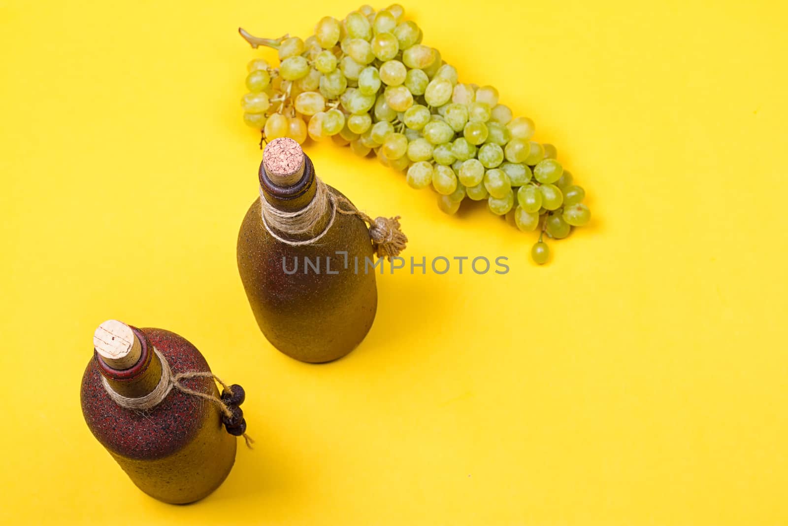 bottle of white wine with grapes on a yellowbackground