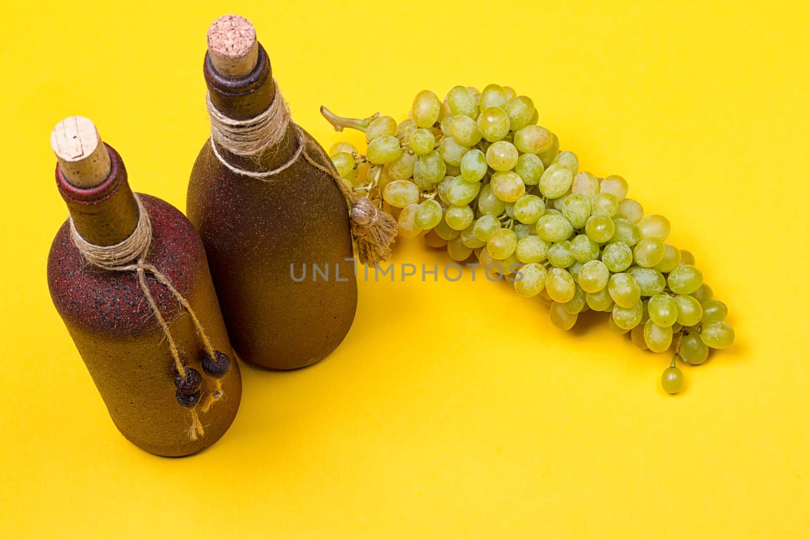 bottle of white wine with grapes on a yellowbackground