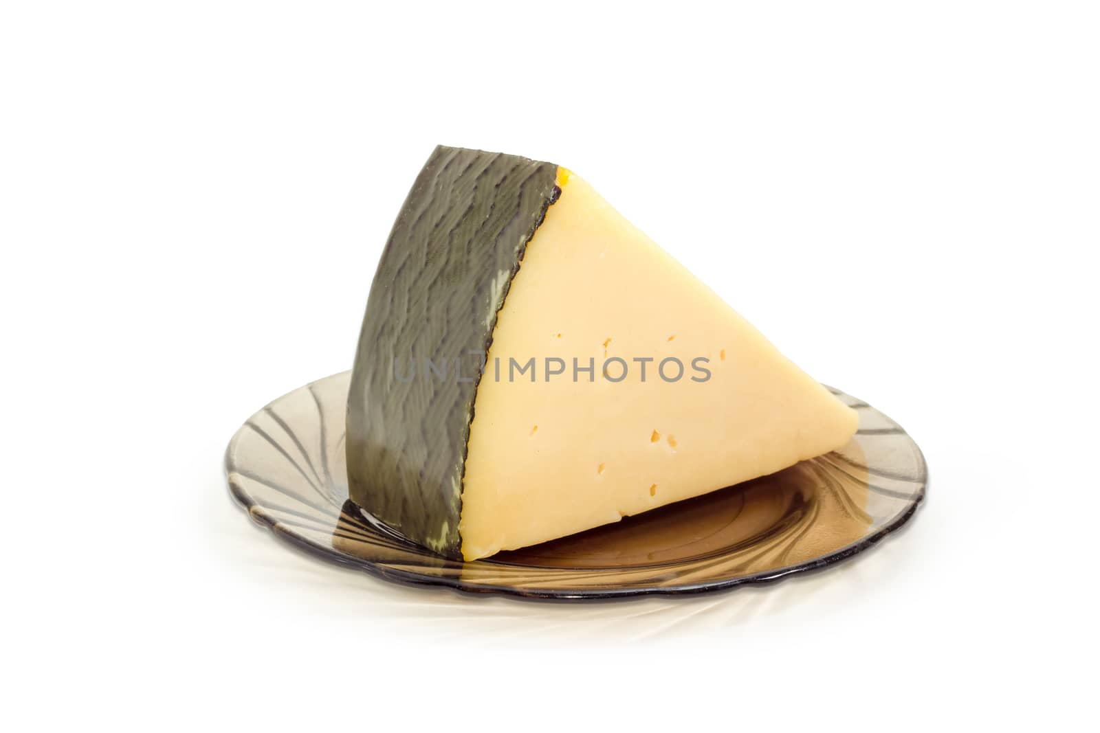 Piece of the hard cheese on the dark glass saucer on a light background
