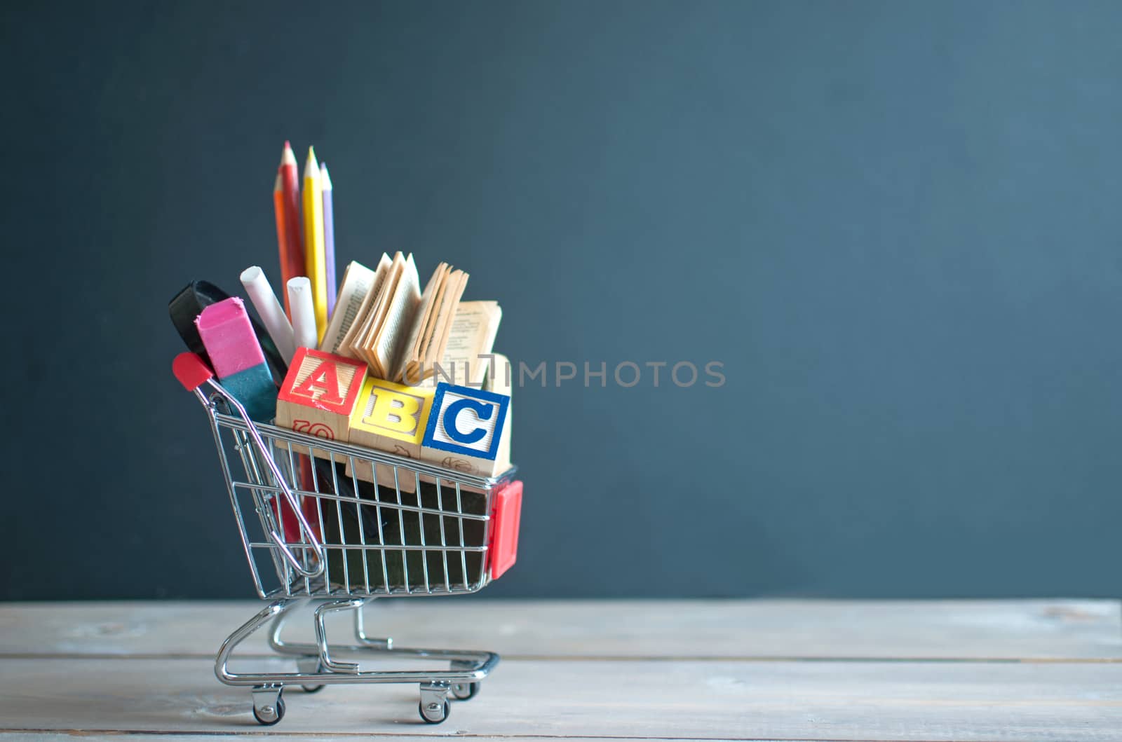 Shopping cart filled with stationery merchandise against chalkboard