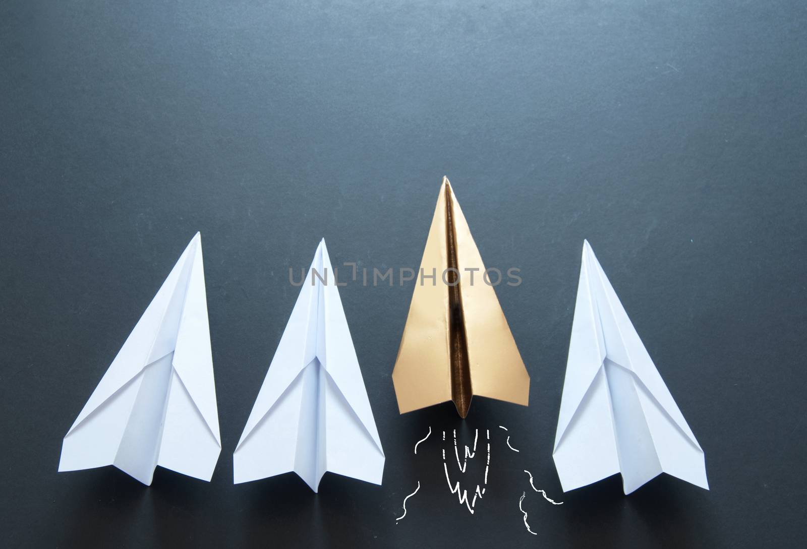 Gold paper plane standing out in a line 