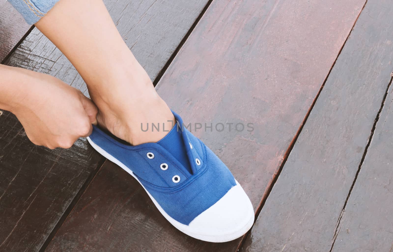 Closeup woman tying sneaker shoes on wood floor, vintage tone