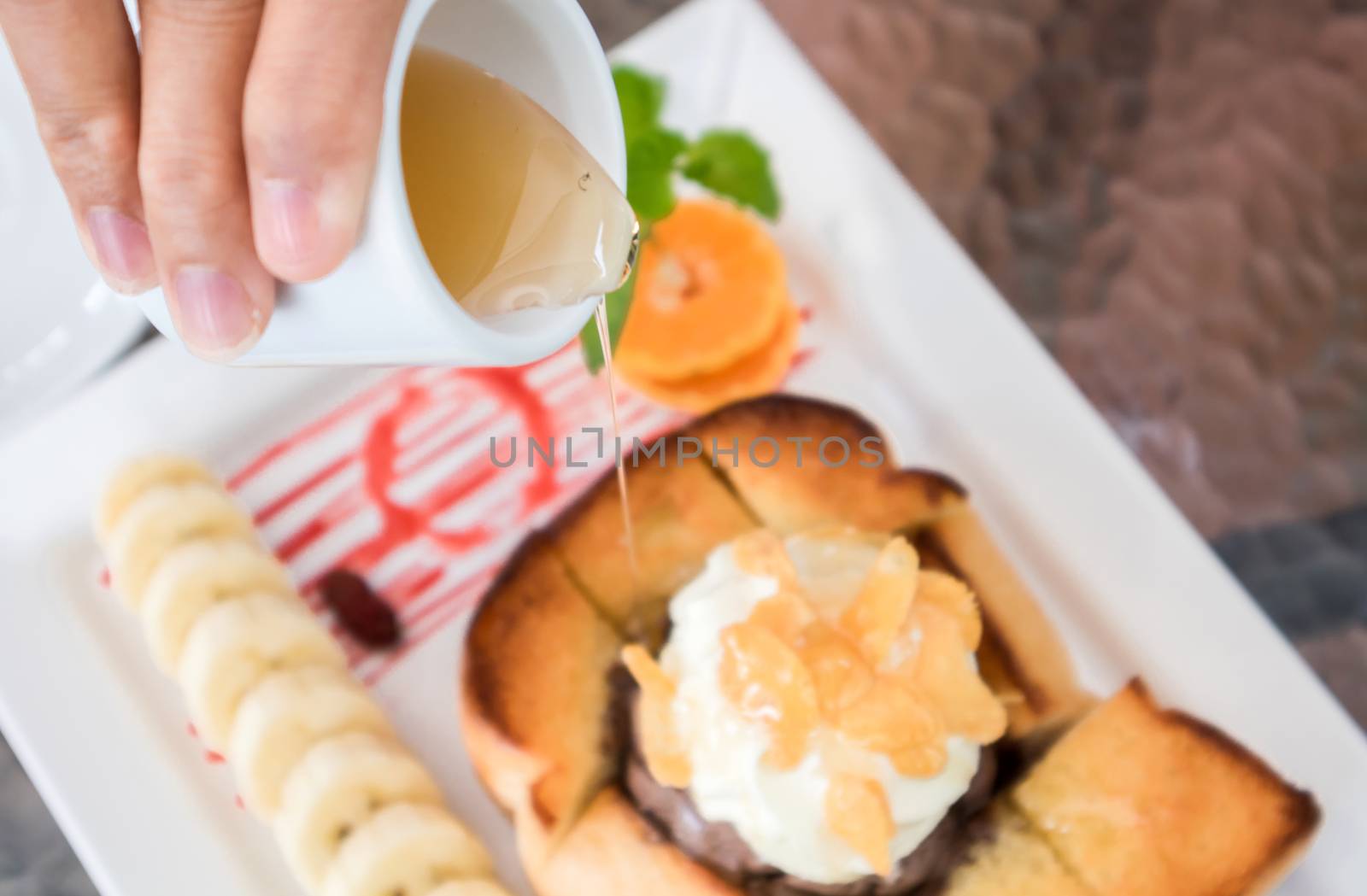 Closeup top view woman hand pouring honey on Honey Toast, selective focus