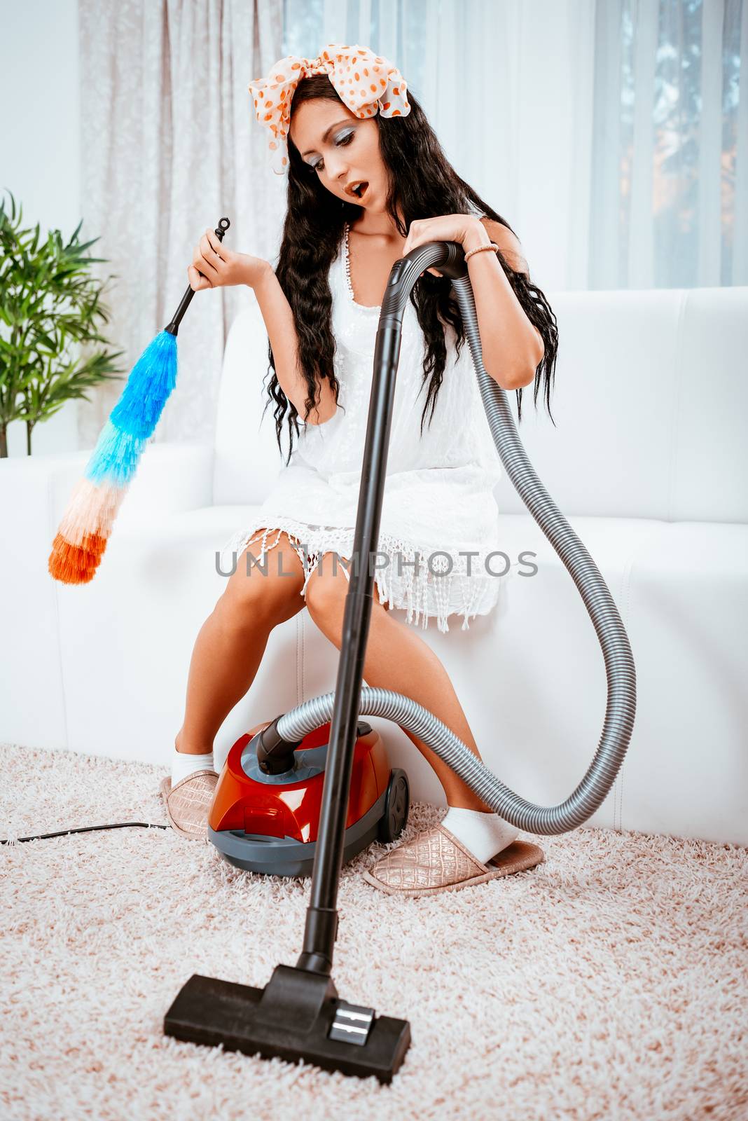 Bored young housewife standing leaning on vacuum cleaner tired of housework.