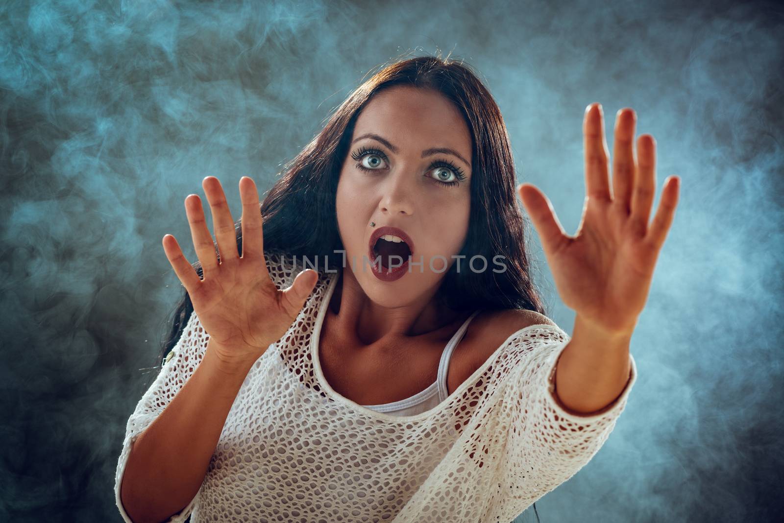 Young stressed woman scared looking through smoke and seeking safety.