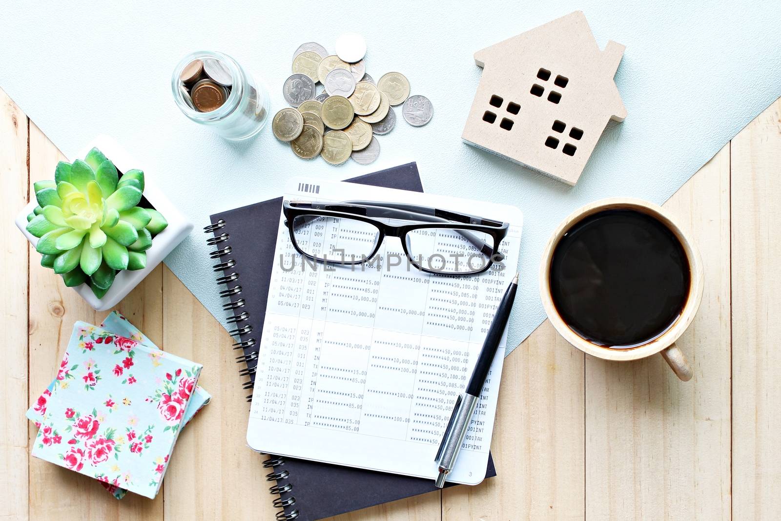 Business, finance, property ladder or mortgage loan concept : Top view or flat lay of saving account passbook or financial statement, wood house model, and coins on office desk table