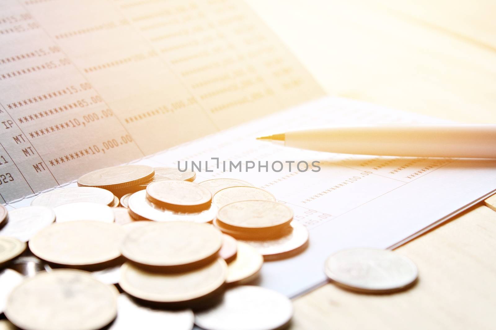 Business, finance, saving money, banking, loan, investment, taxes or accounting concept : Coins and pen on saving account book or financial statement