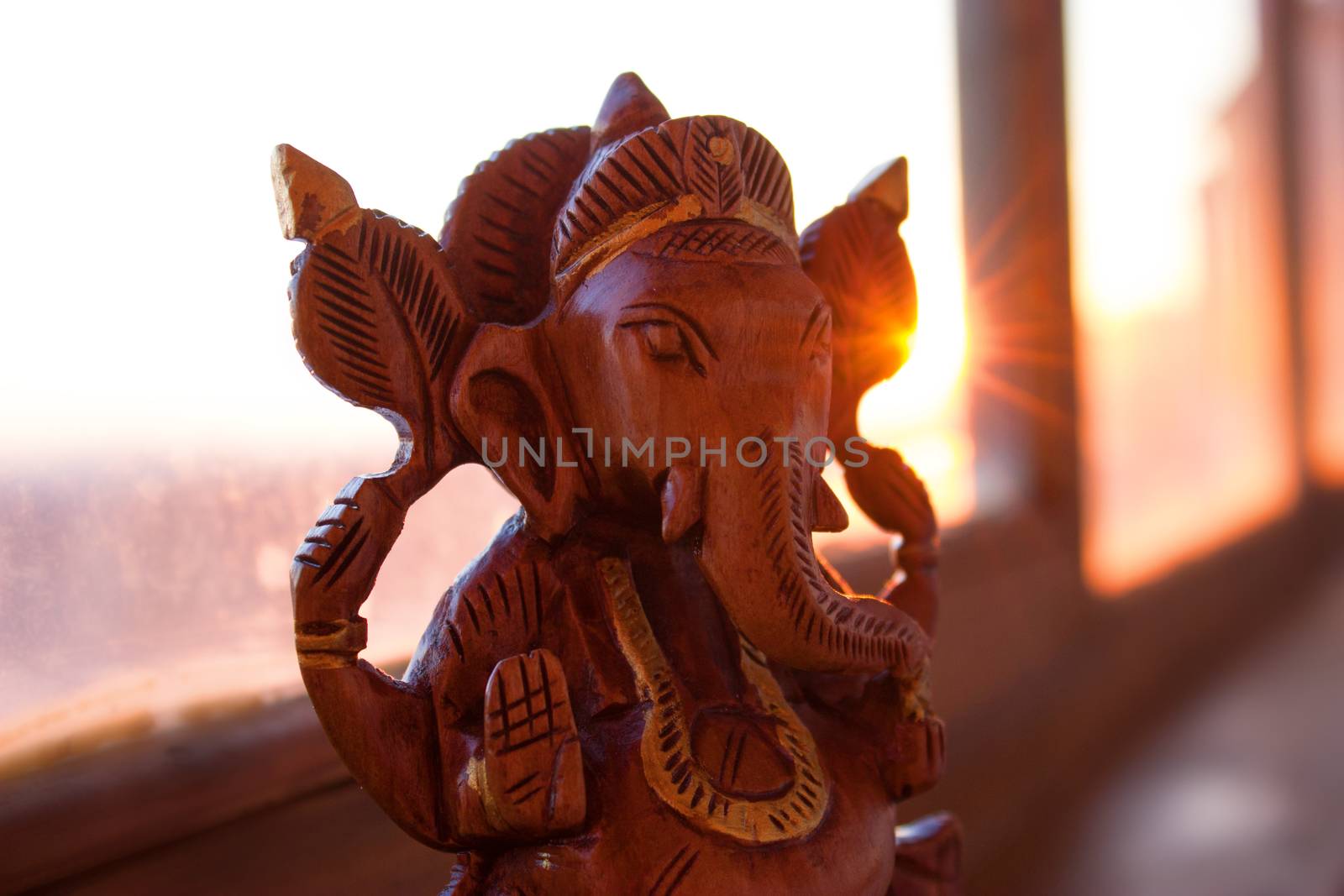 wooden figurine of indian god ganesha in warm sunlight
