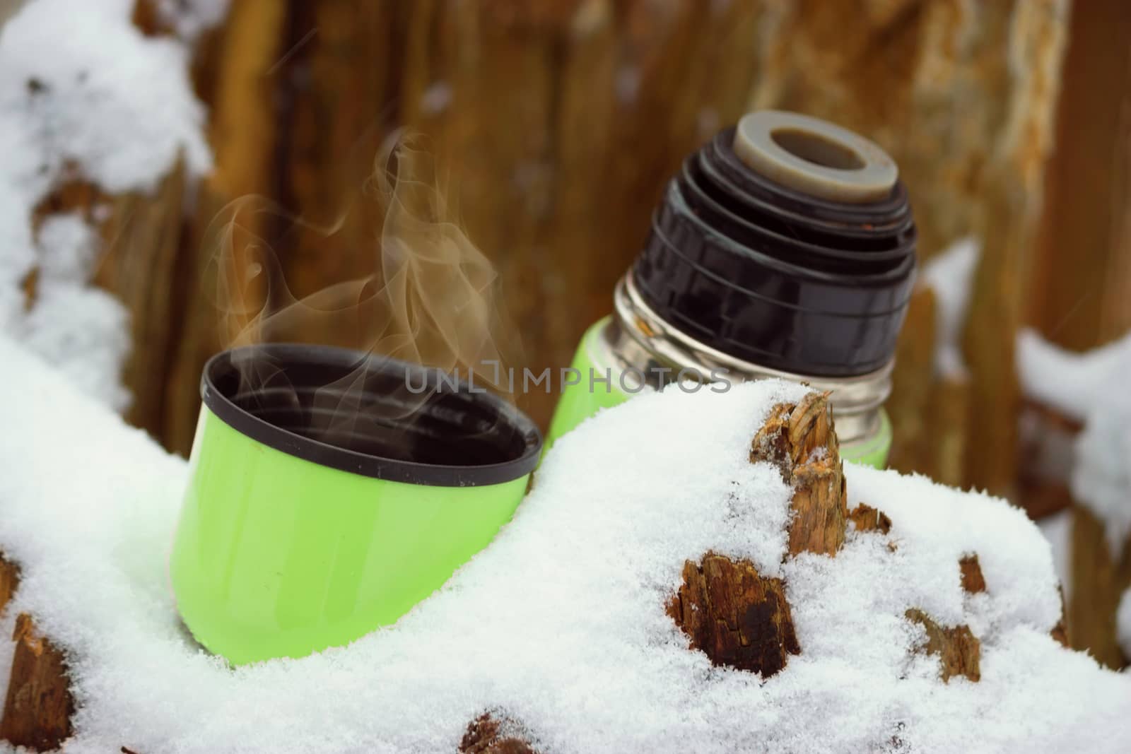 flask of hot tea winter forest background