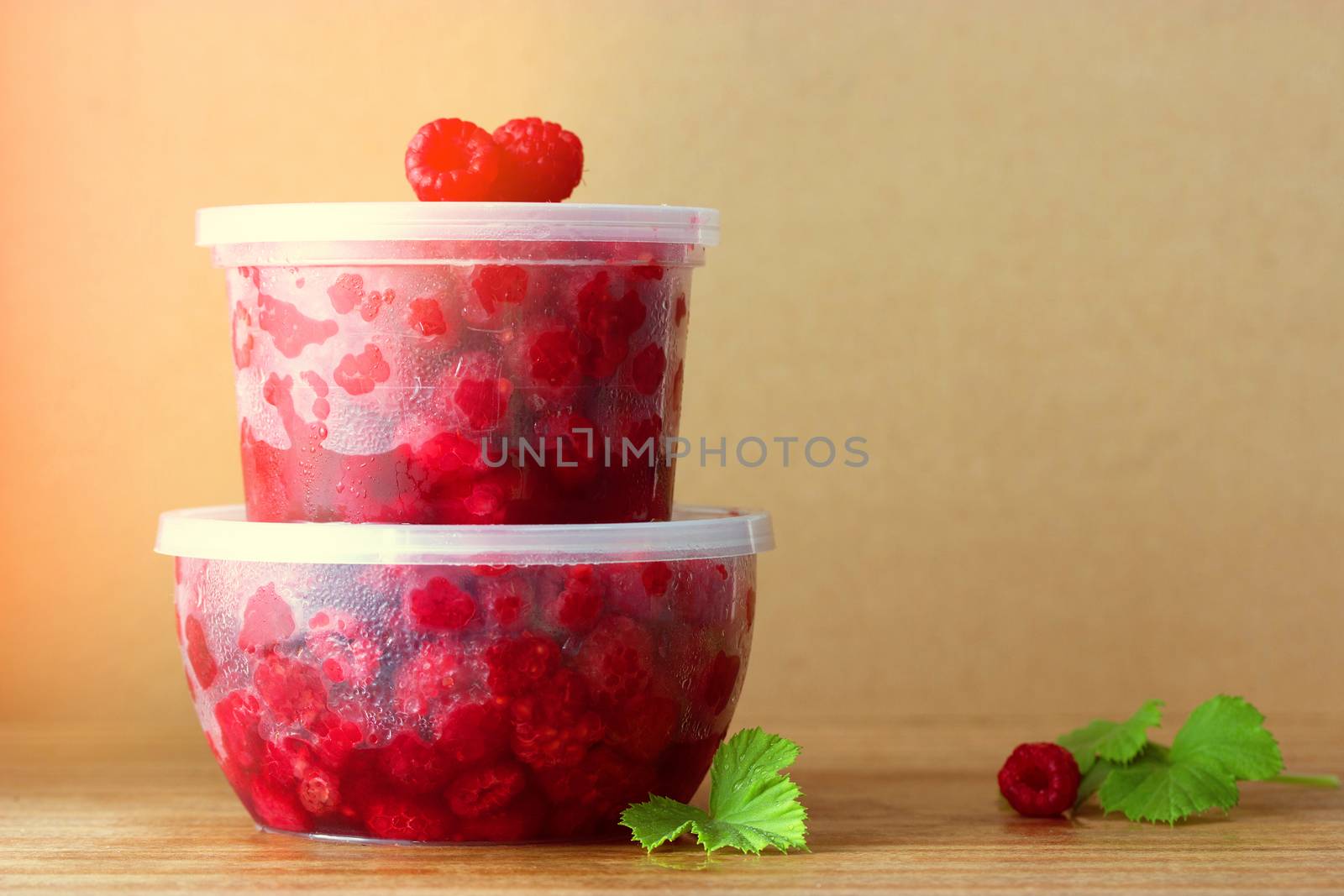 Raspberry in the round box with leaf of mint on the old wood background