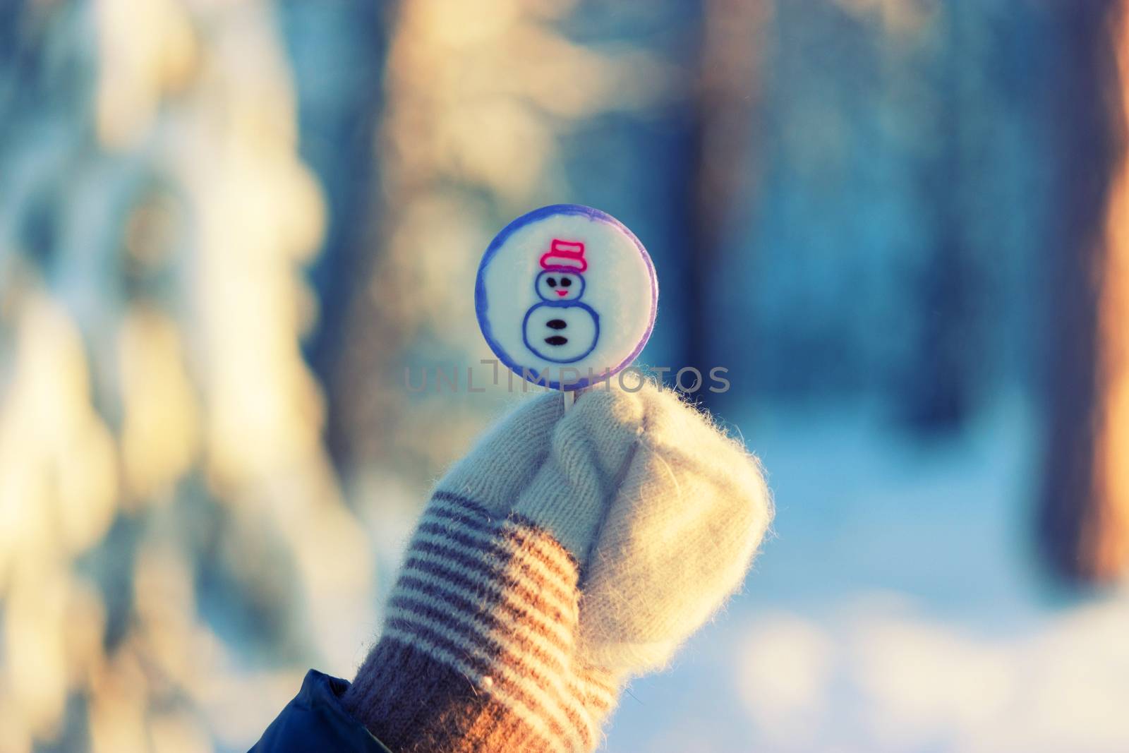 lollipop on stick in hand in mitten. snow background by liwei12