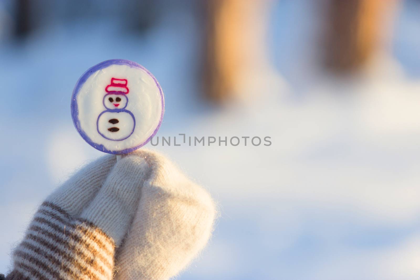 lollipop on stick in hand in mitten. snow background. christmas sweets concept