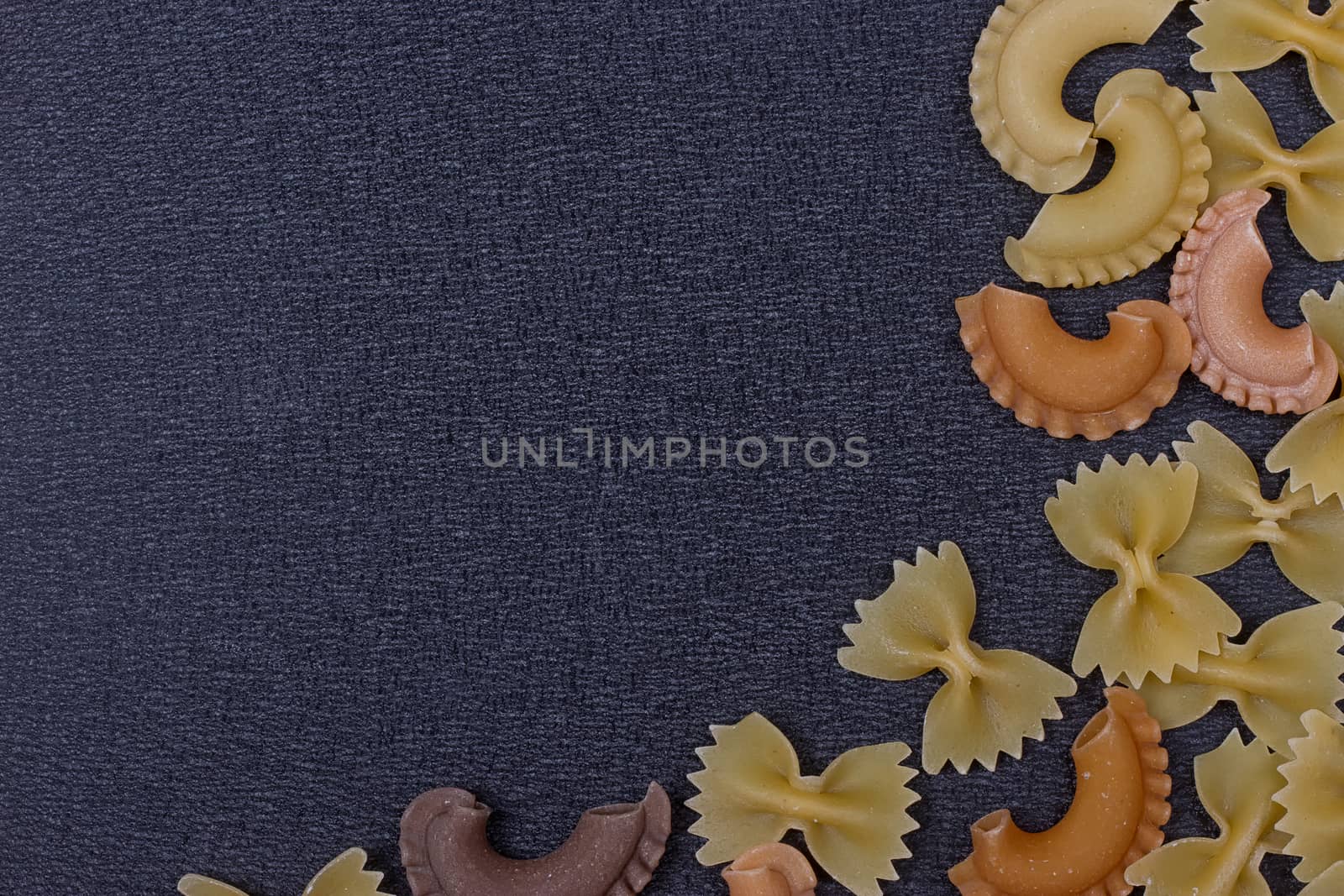 Variety of types of Italian pasta background. Set of raw dry pasta on a black slate background.
