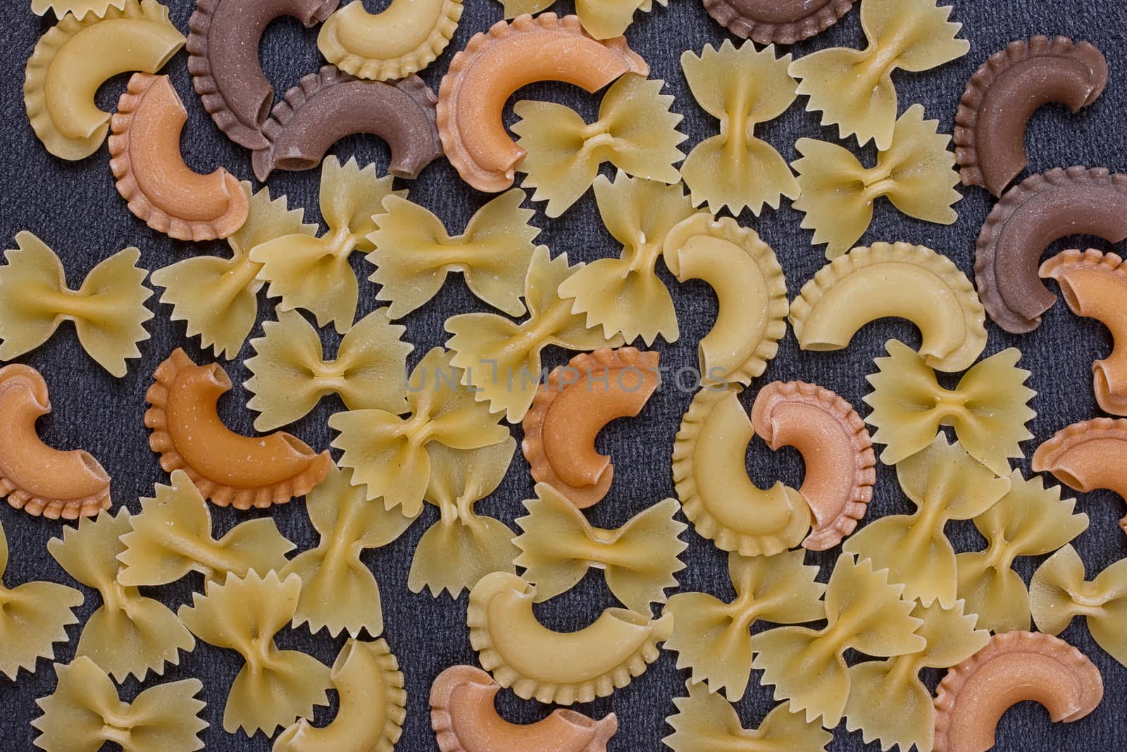 Variety of types of Italian pasta background. Set of raw dry pasta on a black slate background.