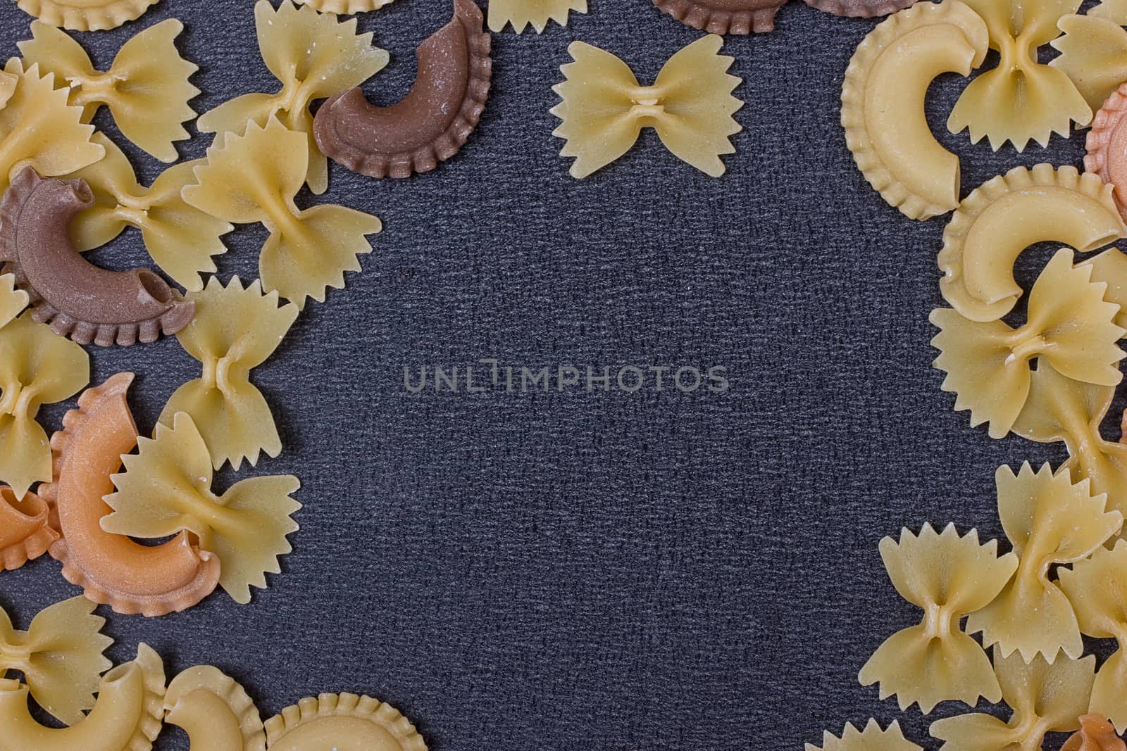 Variety of types of Italian pasta background. Set of raw dry pasta on a black slate background.