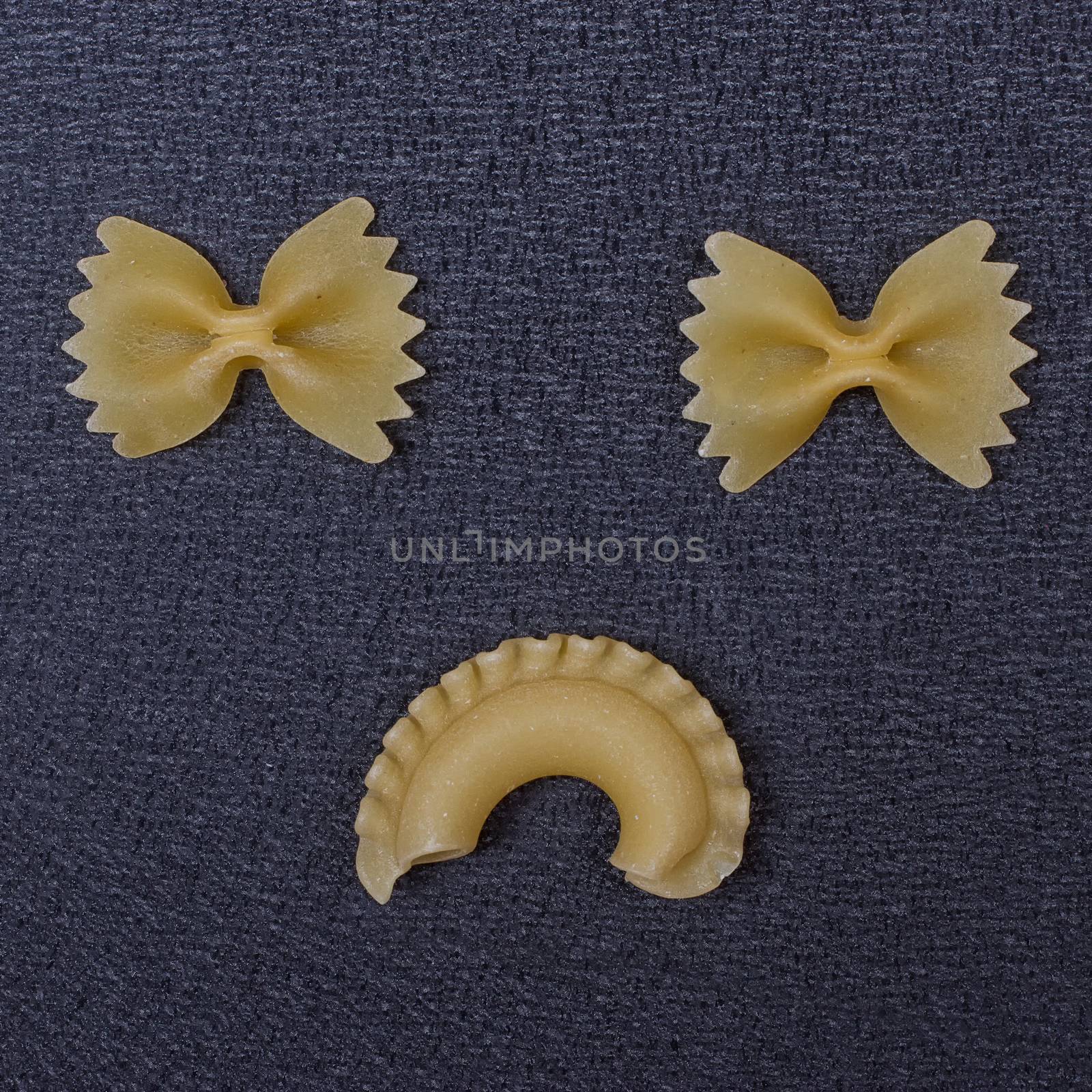 Smiling raw pasta on the black background