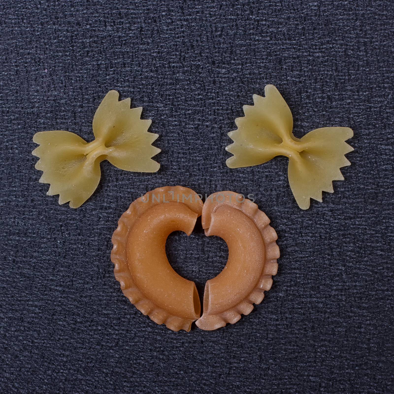 Smiling raw pasta on the black background