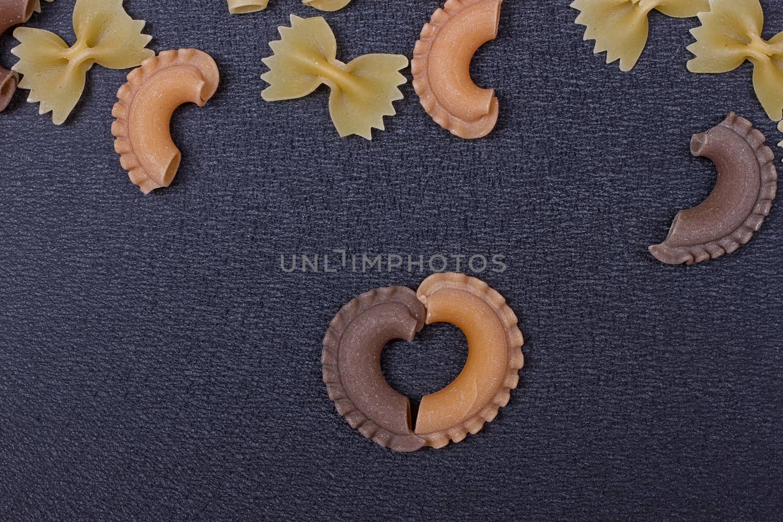 Variety of types of Italian pasta background. Set of raw dry pasta on a black slate background.