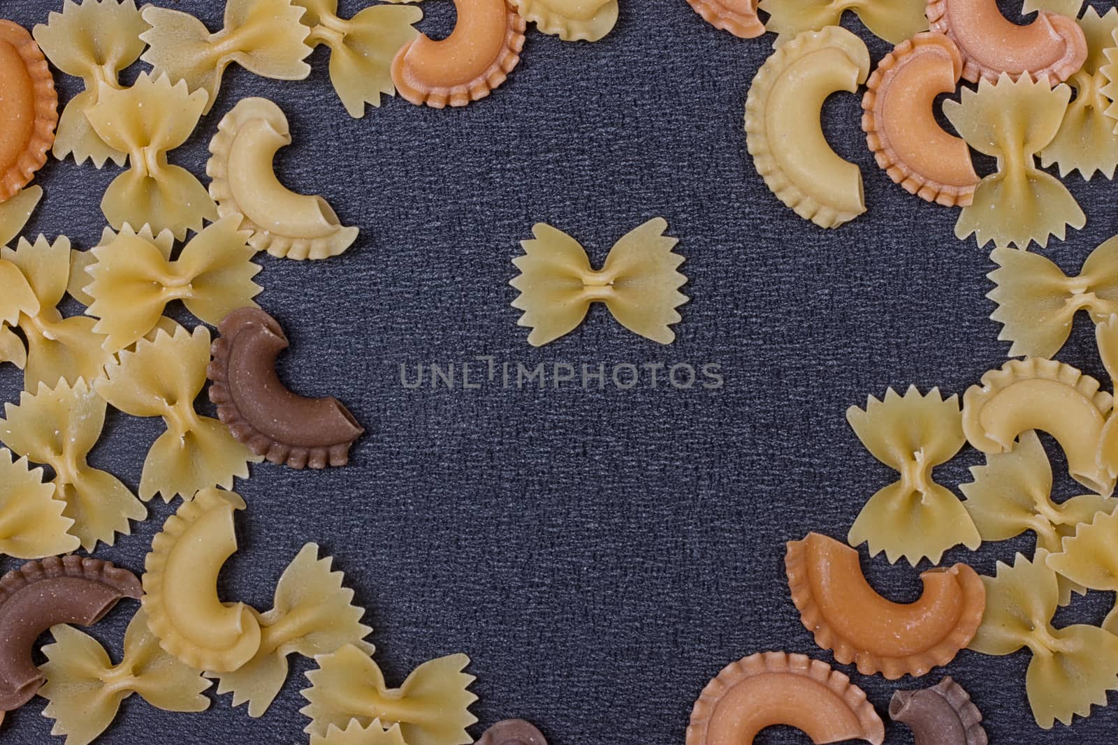 Variety of types of Italian pasta background. Set of raw dry pasta on a black slate background.