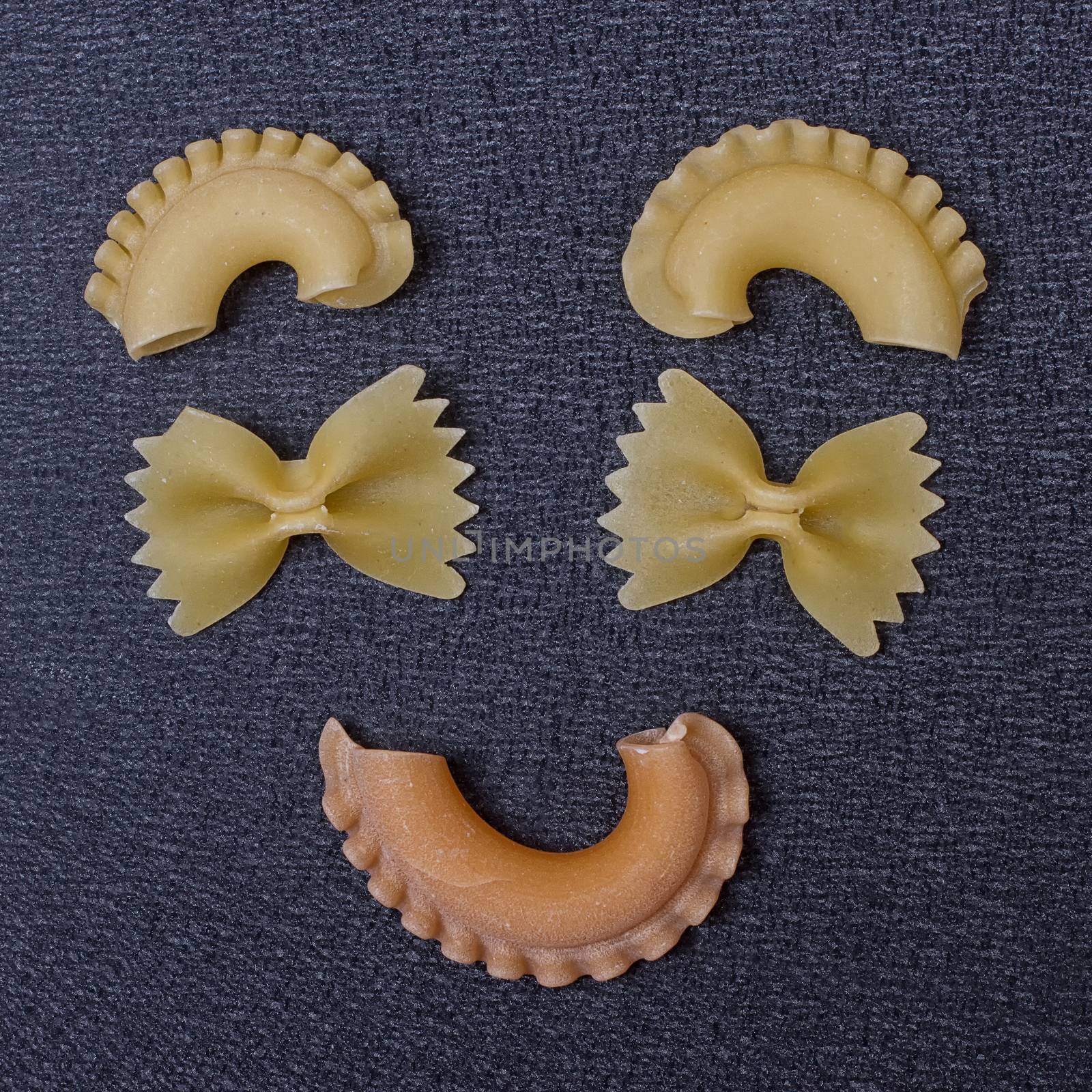 Smiling raw pasta on the black background