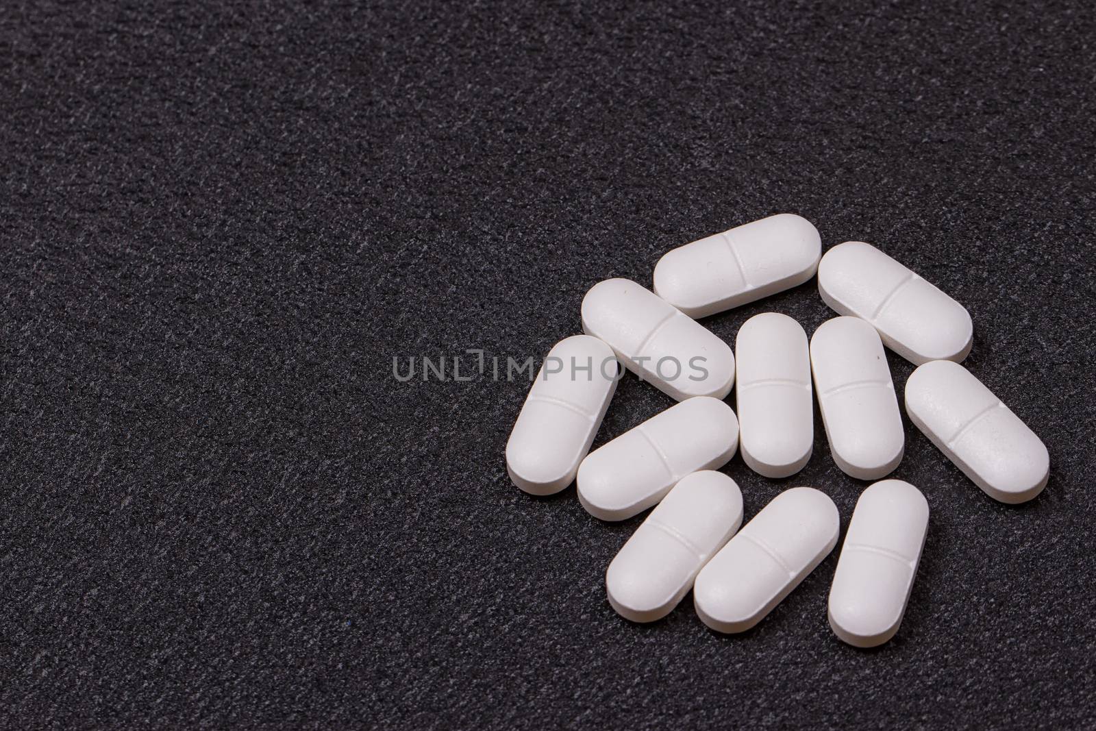 close up white pills on black background.