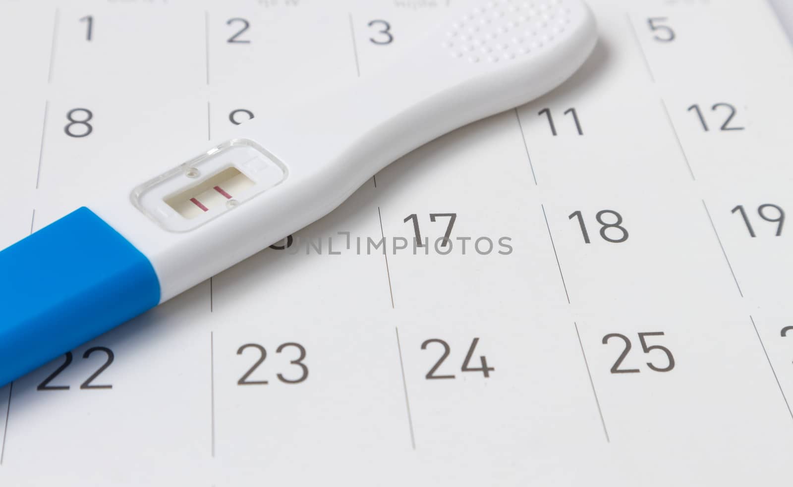 Pregnancy test on calendar background, health care concept