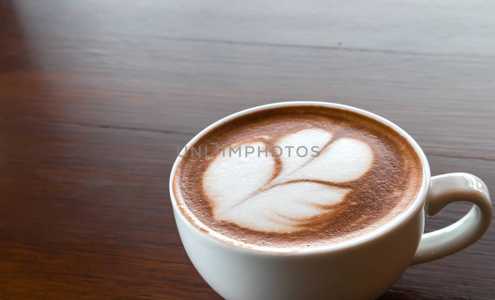 Closeup cup of hot coffee tulip latte art on wood table by pt.pongsak@gmail.com