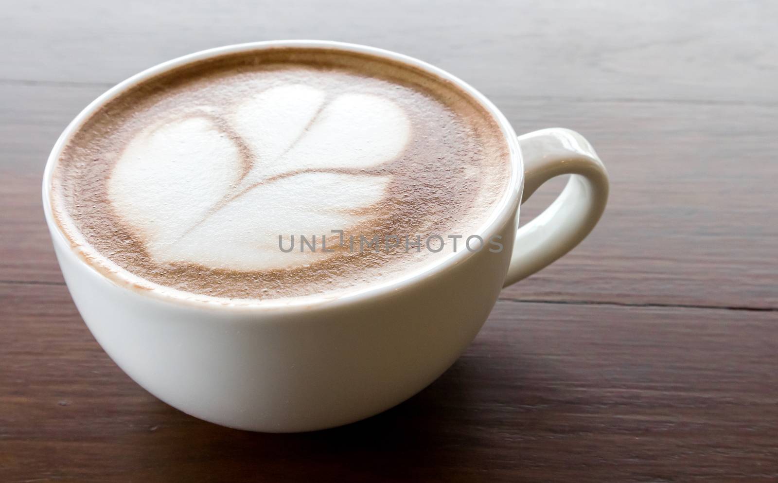 Closeup cup of hot coffee tulip latte art on wood table