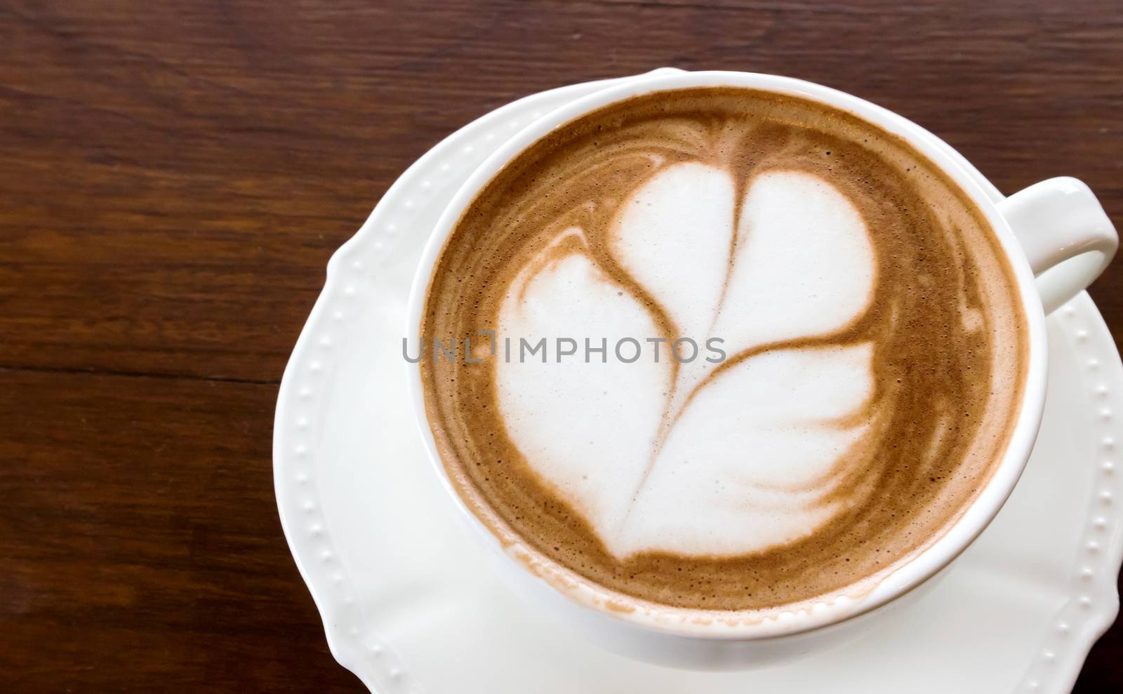 Closeup cup of hot coffee tulip latte art on wood table